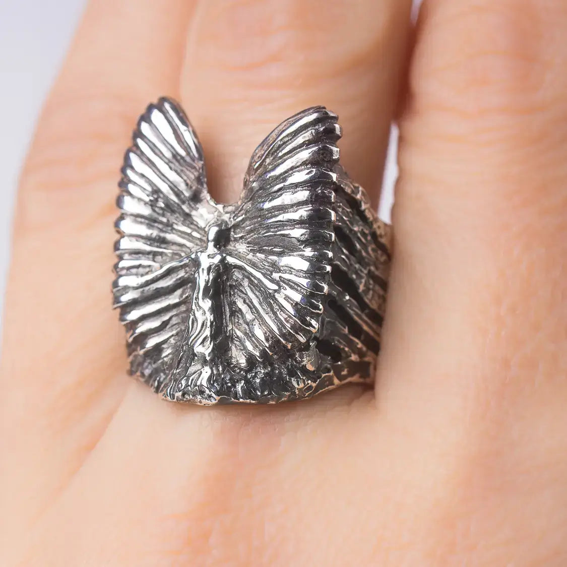 Sterling silver artistic angel wings ring, spiritual statement jewelry piece on finger.