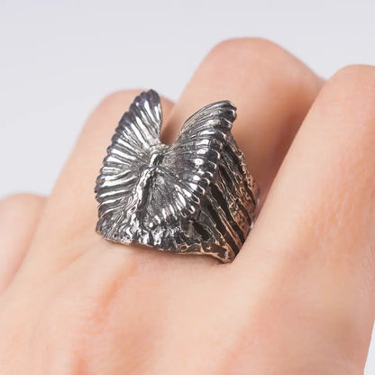 Sterling silver guardian angel ring with abstract winged design, showcasing artistic and spiritual elegance on a finger.