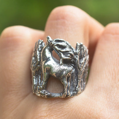 elk ring in sterling silver, woods background, front view, worn on finger.