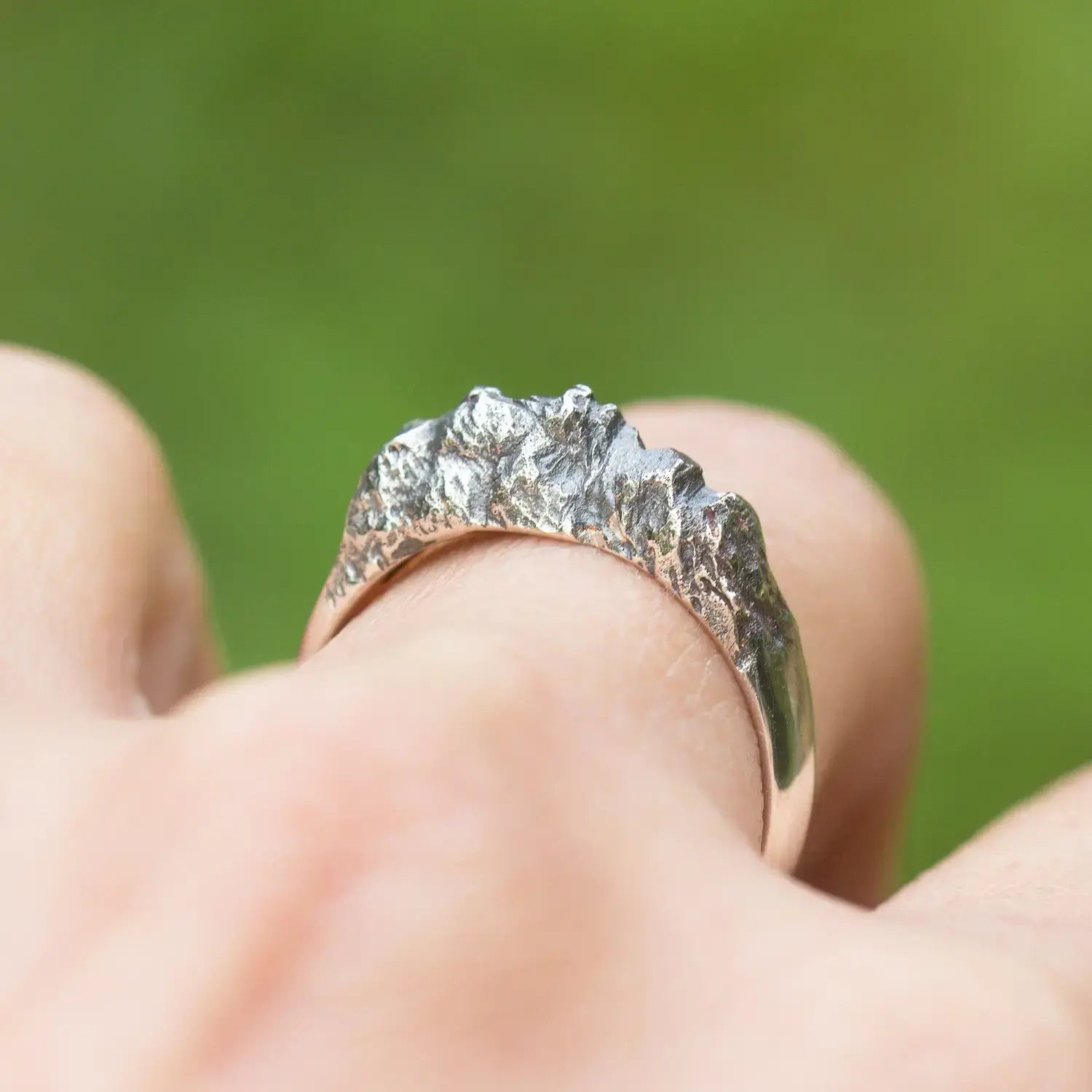 Sterling silver mountain range ring with textured rock design on a woman's finger, showcasing organic textures and polished band.