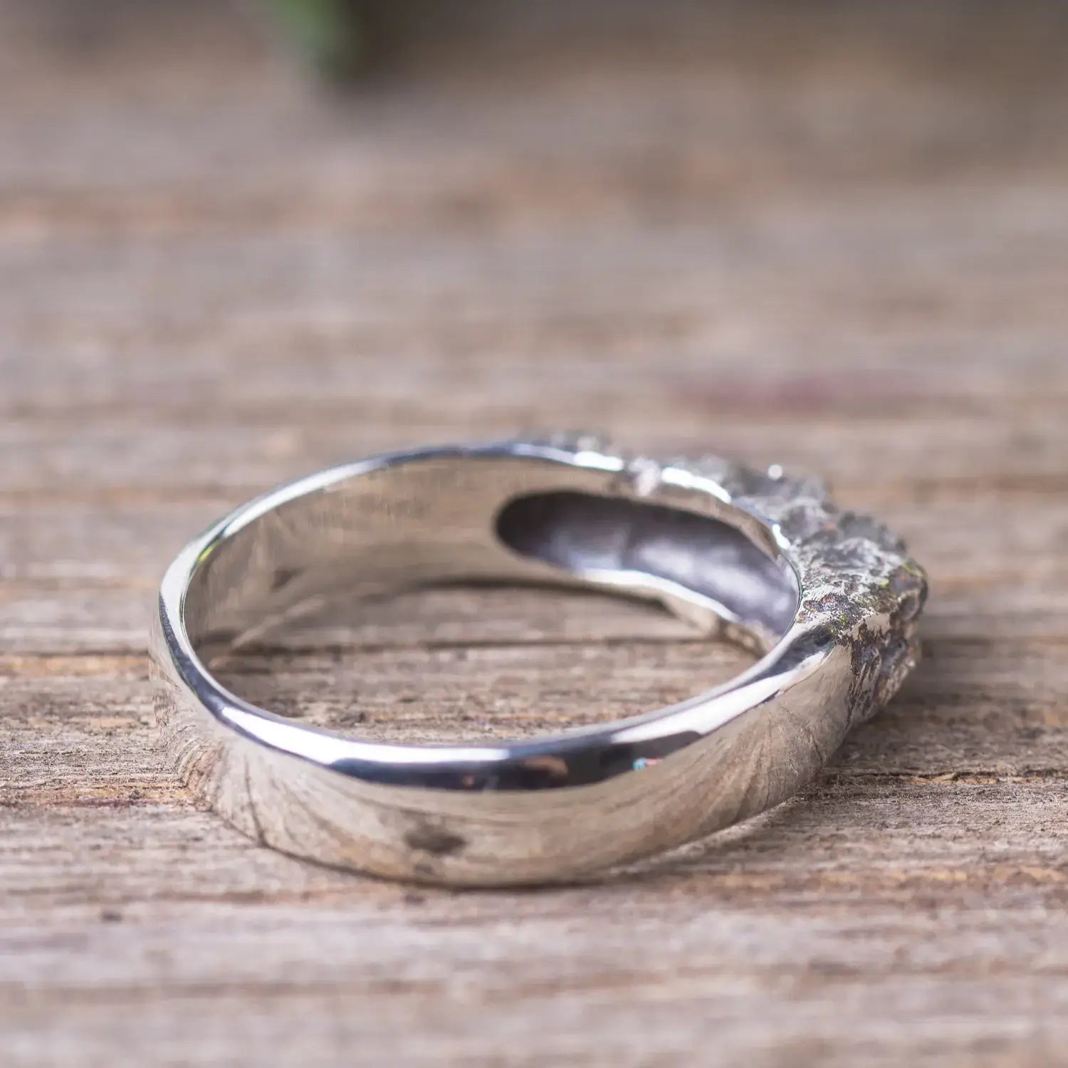 Sterling silver textured mountain range ring with rock style design for women on wooden surface.