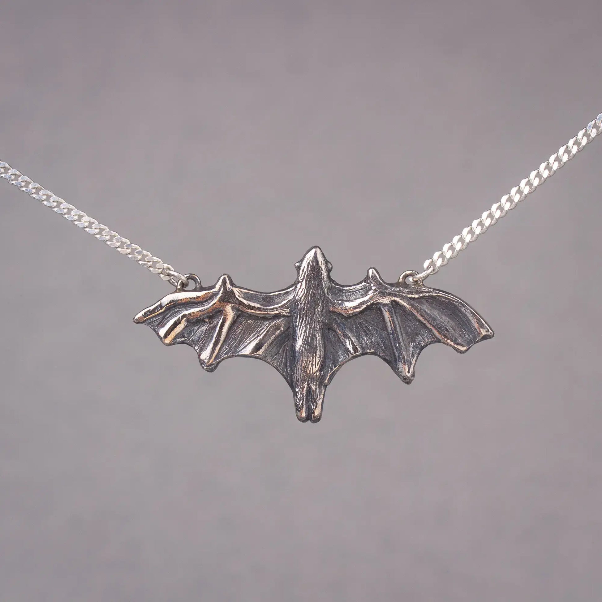 Silver bat pendant necklace featuring a large flying fruit bat, perfect statement piece for bat lovers and Halloween jewelry enthusiasts.