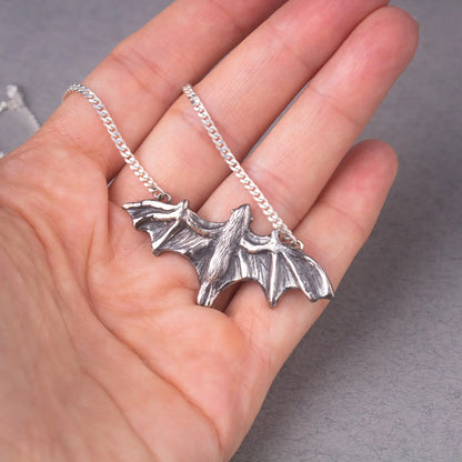 Sterling silver bat pendant necklace in hand, handcrafted large flying bat jewelry, statement piece for bat lovers and nature enthusiasts.