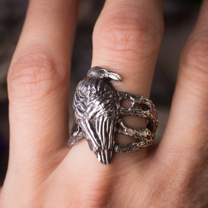 Handcrafted silver crow ring with intricate bird design on tree branches, perfect for nature and animal lovers.