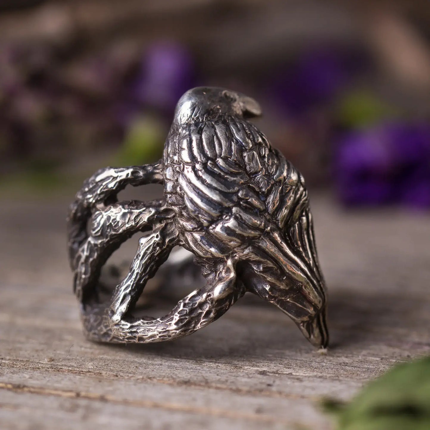 Handcrafted sterling silver crow ring perched on tree branches, showcasing intricate details and mystical design.