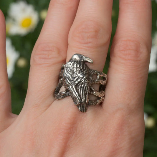 Handcrafted sterling silver crow ring with intricate design on finger, symbolizing nature and mysticism.