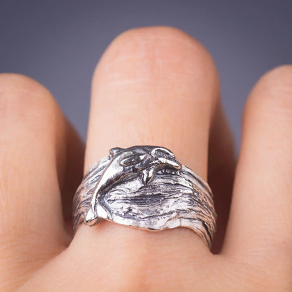 Silver dolphin ring with wide wavy band, ocean-inspired animal ring, sterling silver sea life jewelry on finger.