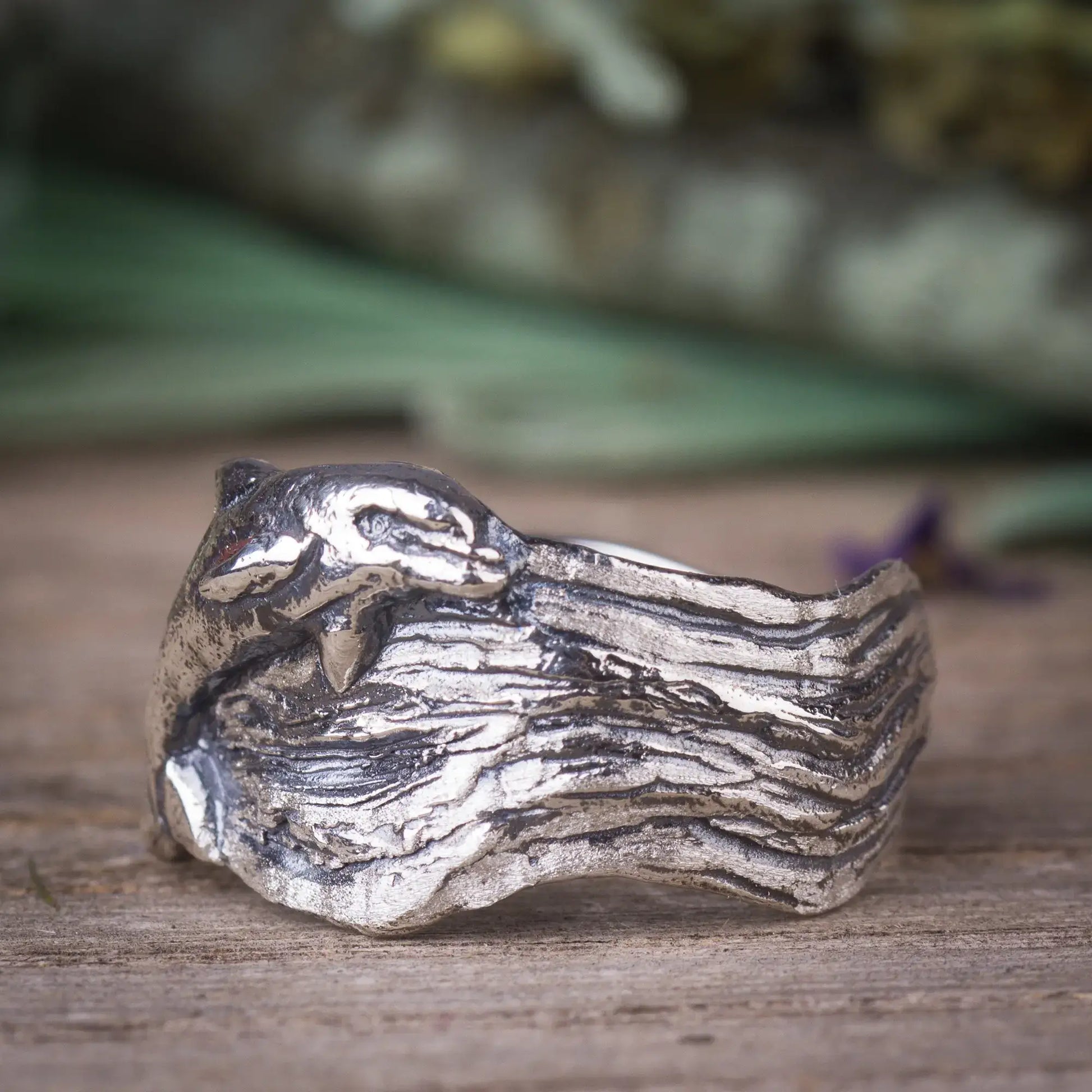 Sterling silver dolphin ring with wide wavy band, designed to resemble ocean waves, showcasing a lifelike jumping dolphin.