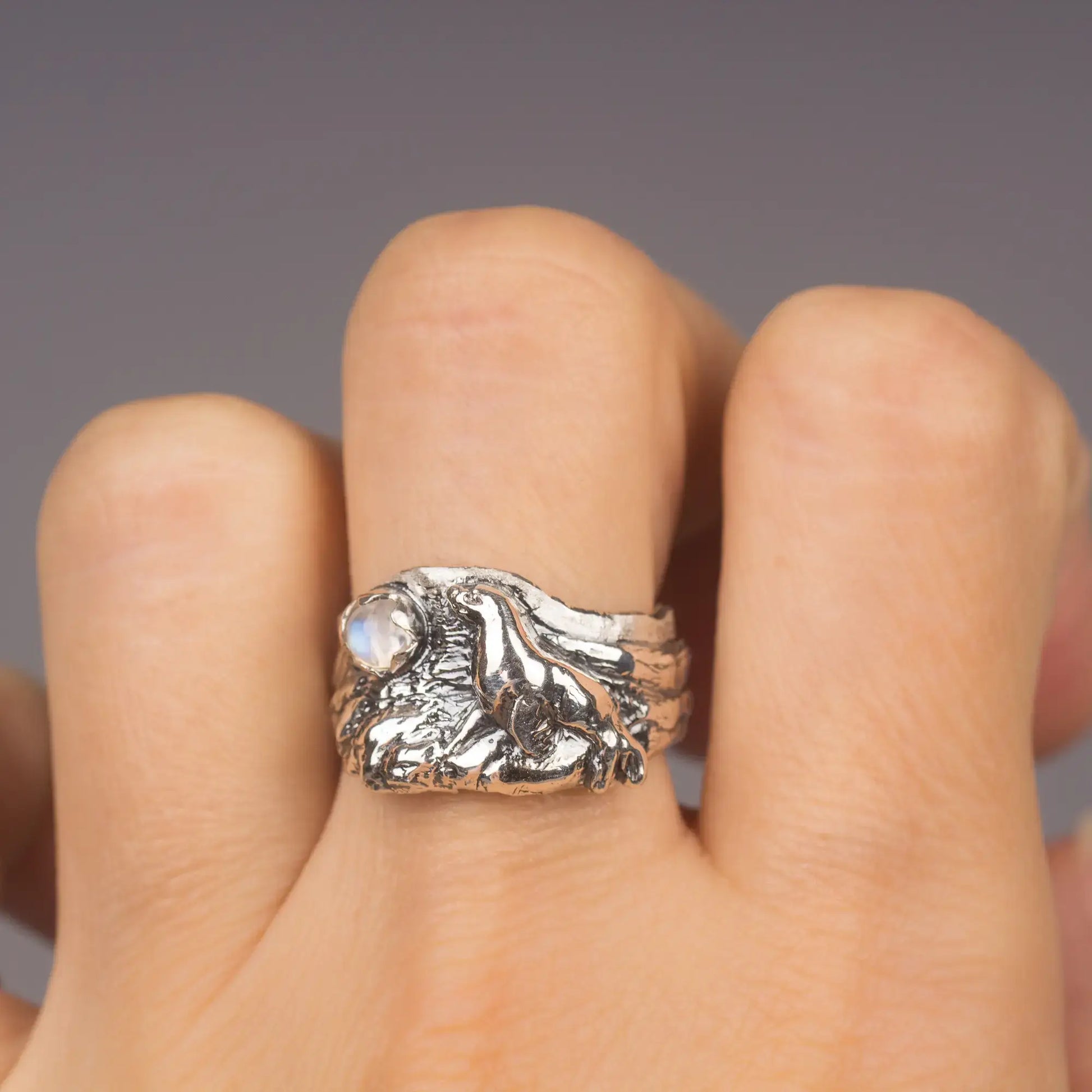 Sterling silver sea lion ring with moonstone, featuring intricate ocean and rocky beach design.