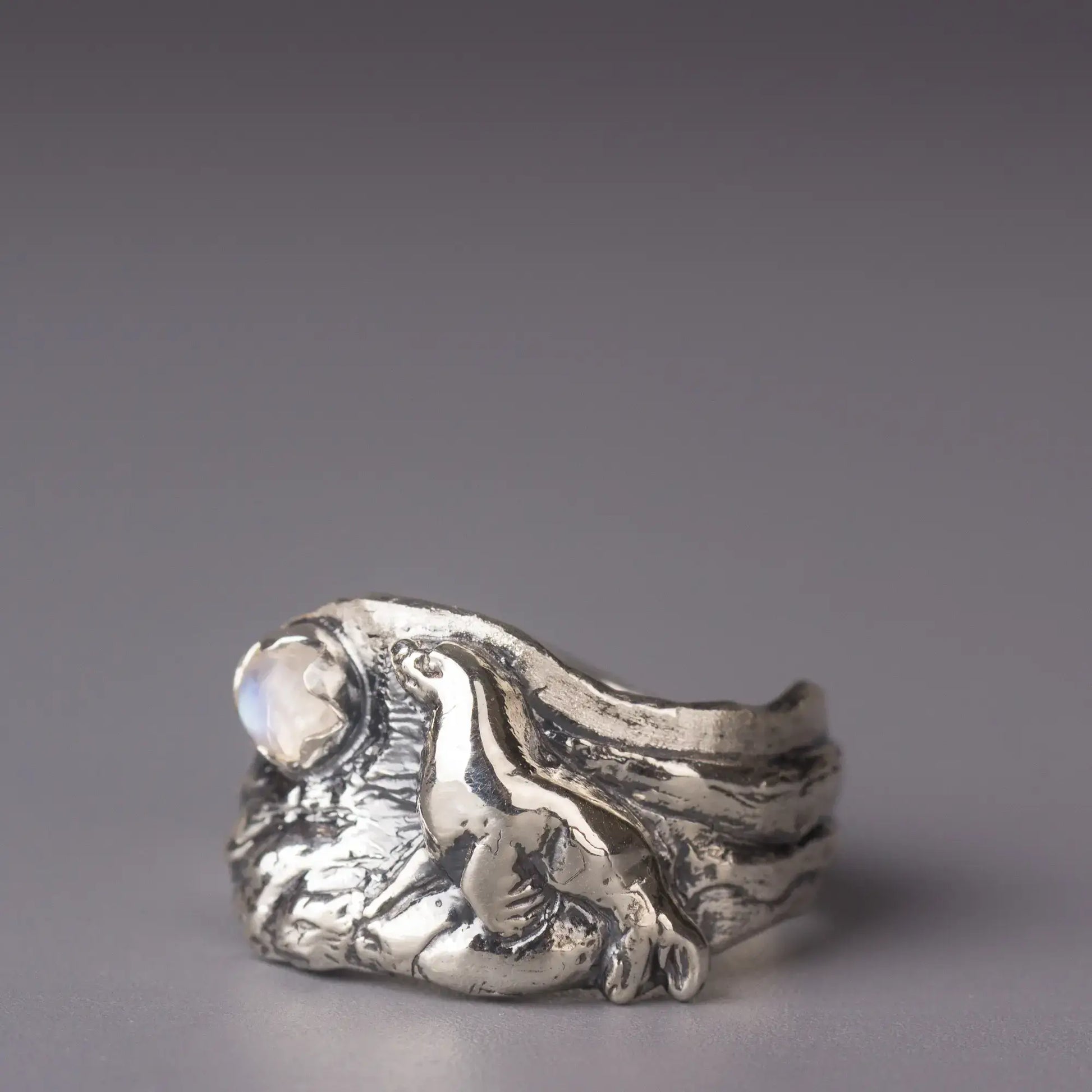 Sterling silver sea lion ring with moonstone, featuring a detailed realistic design and wavy ocean background. Perfect for sea lovers.