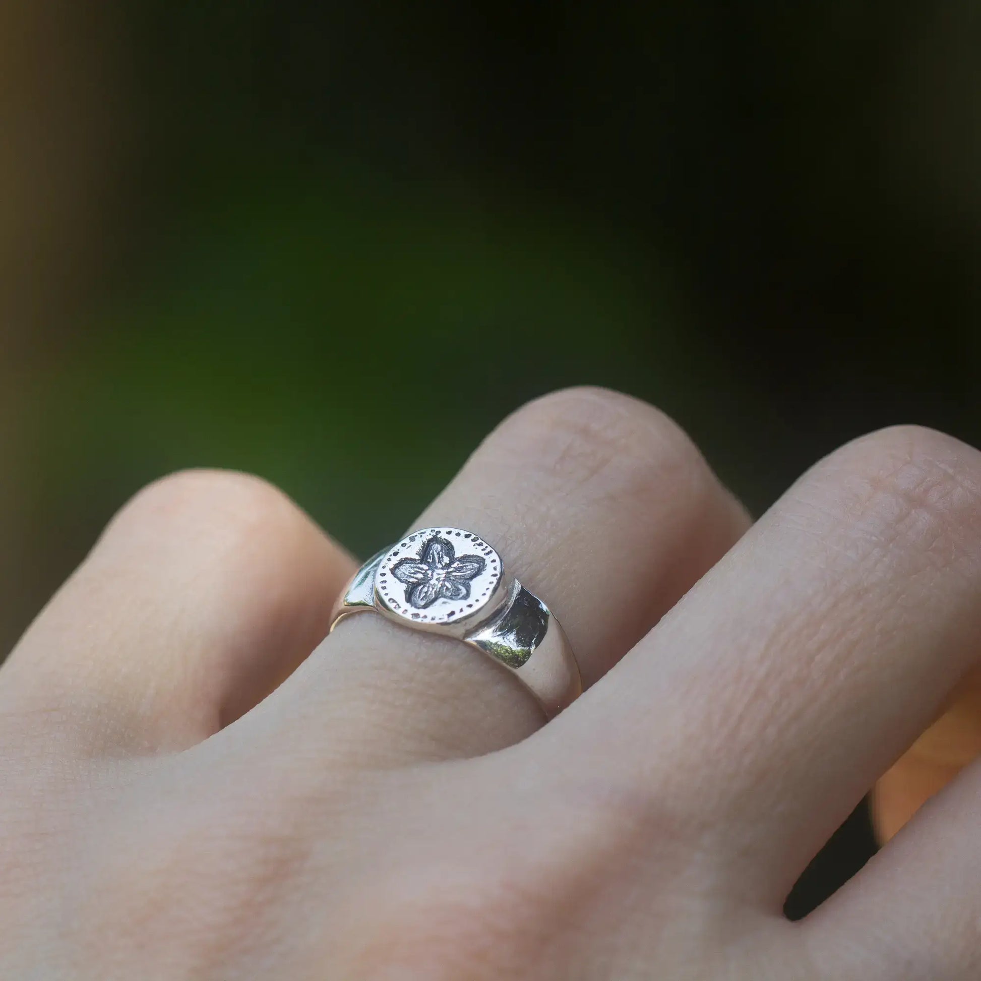 Dainty sterling silver Pimpernel flower signet ring with antique style design on finger.