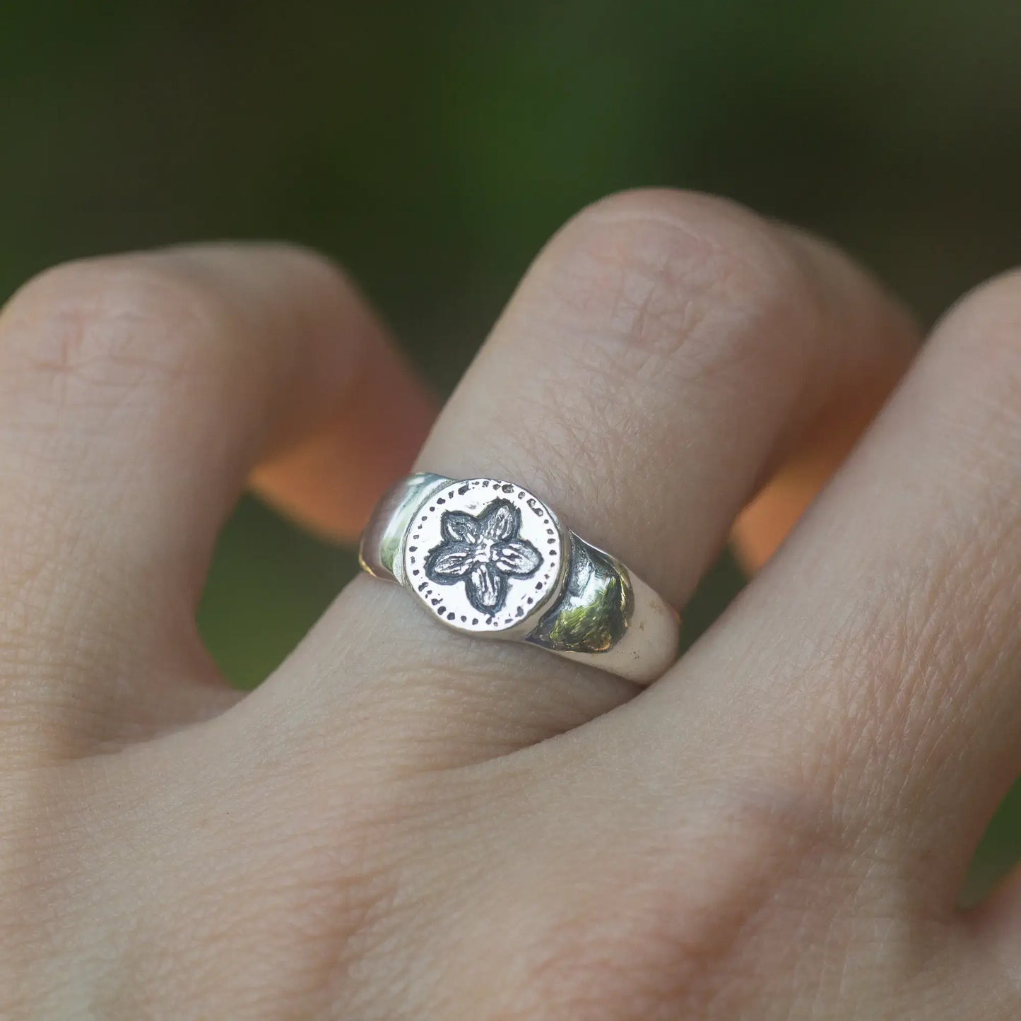 Sterling silver antique style flower signet ring with Pimpernel design on hand.