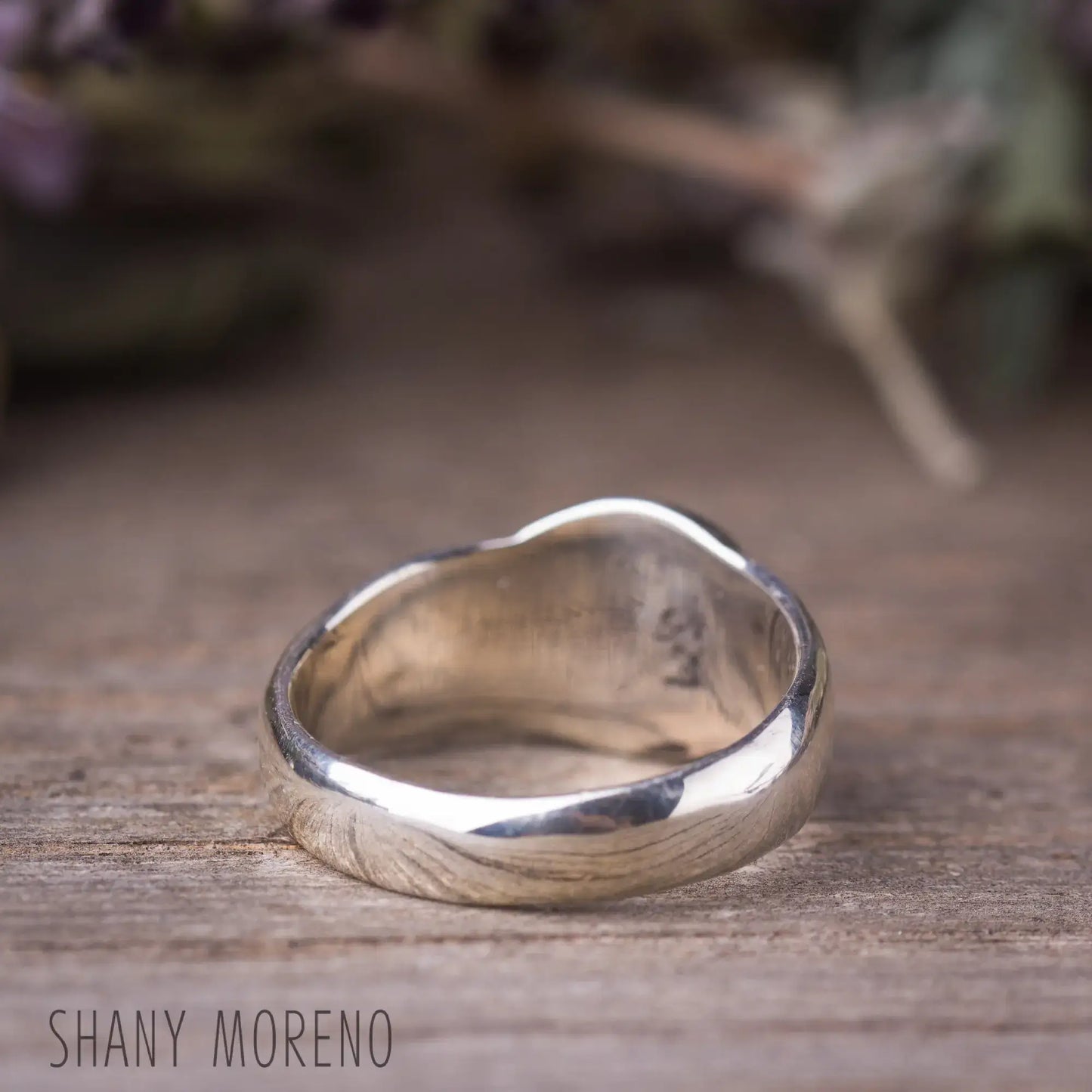 Antique style sterling silver signet ring on wooden surface, showcasing its elegant design and craftsmanship.