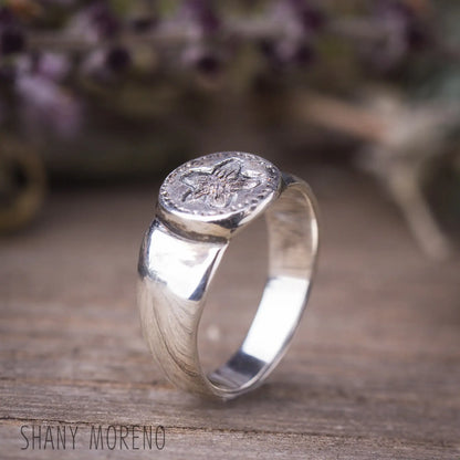 Antique style sterling silver Pimpernel flower signet ring on wooden surface, nature-inspired dainty jewelry.