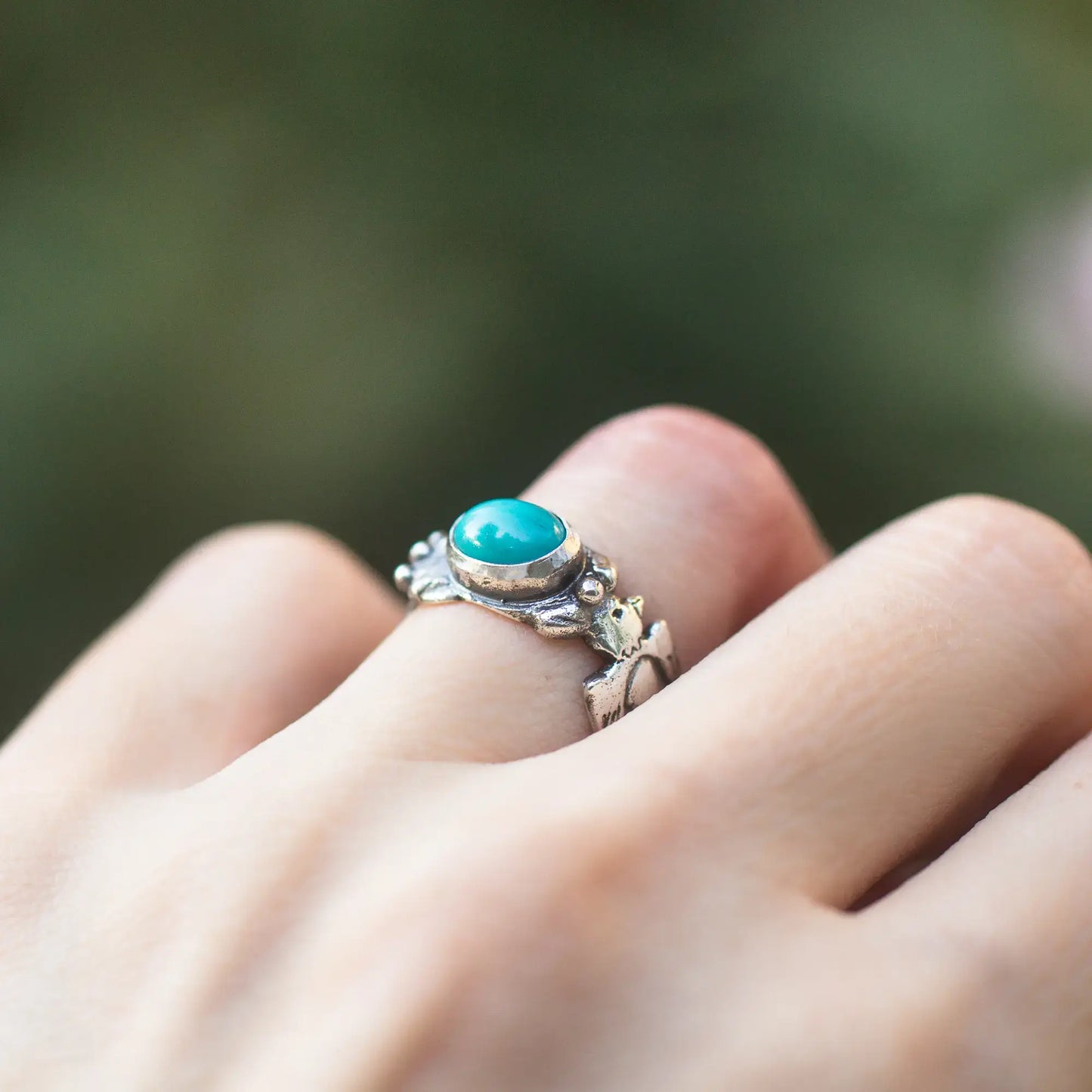 Thunderbird Turquoise Sterling Silver Ring with Feather Design worn on finger, featuring an oval turquoise gemstone.