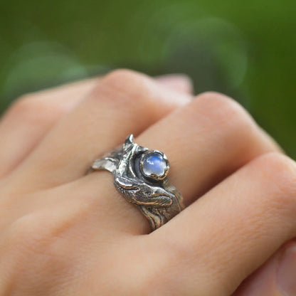 Sterling silver humpback whale ring withmoonstone on a hand, featuring a bold wide band and ocean-inspired design.