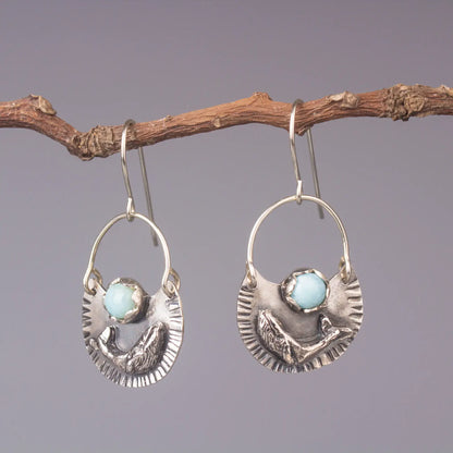 Humpback whale dangle earrings in silver with Larimar gemstone, ocean style statement earrings hanging on a branch.