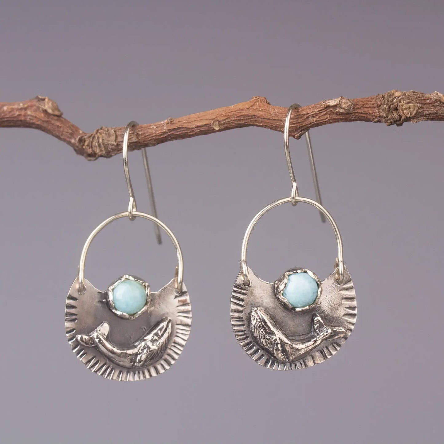 Silver humpback whale dangle earrings with larimar gemstone, ocean style statement jewelry hanging on a twig.