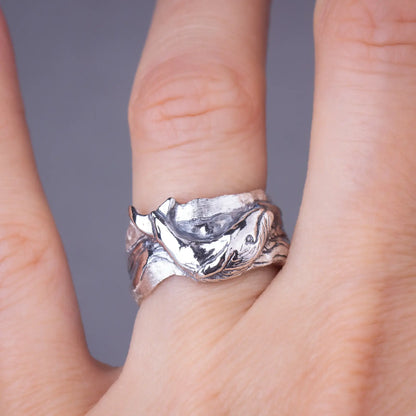 Whale ring in sterling silver with detailed humpback whale design on wide band, worn on a finger.