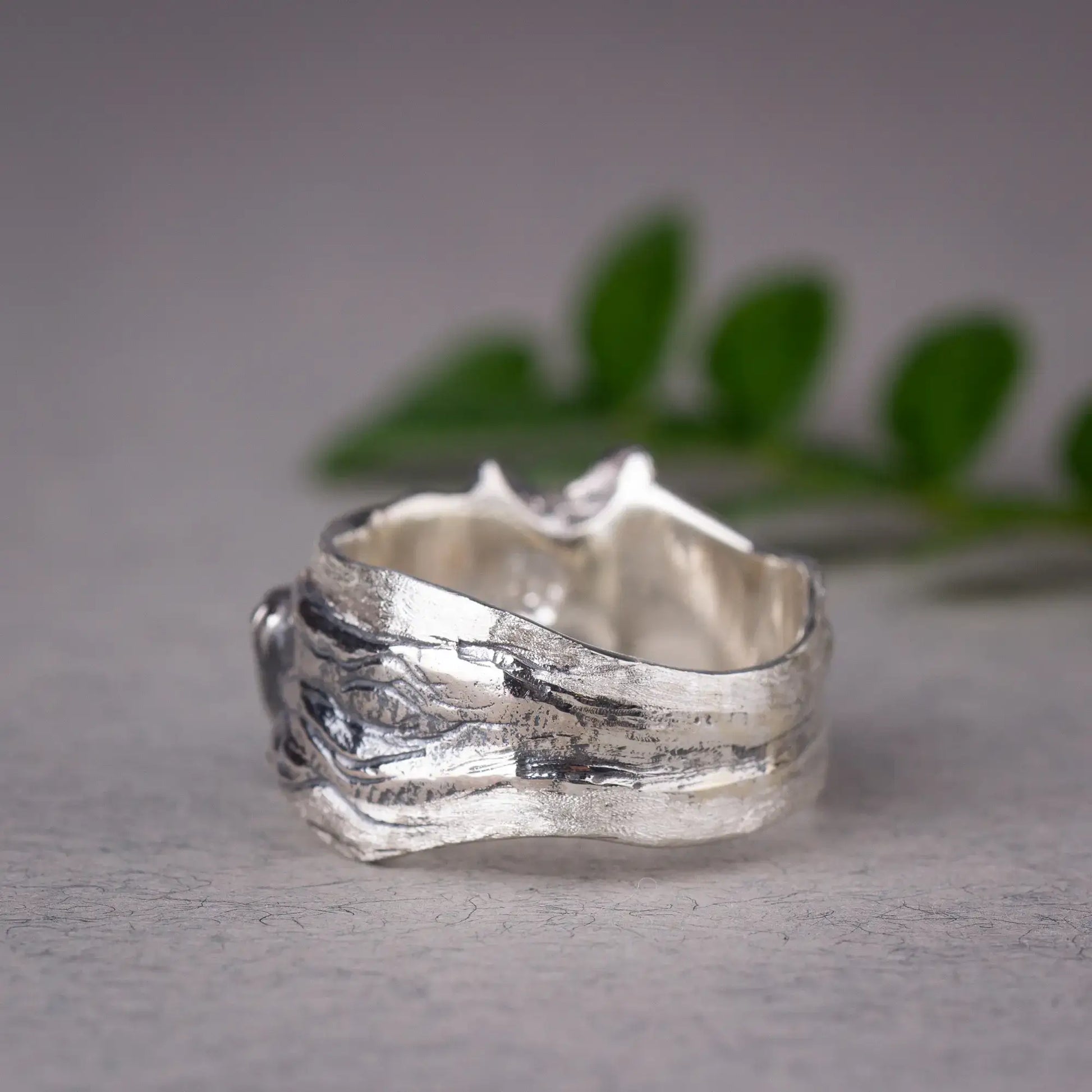 Sterling silver humpback whale ring featuring a detailed whale design gliding across a textured wide band in a nature-inspired setting.